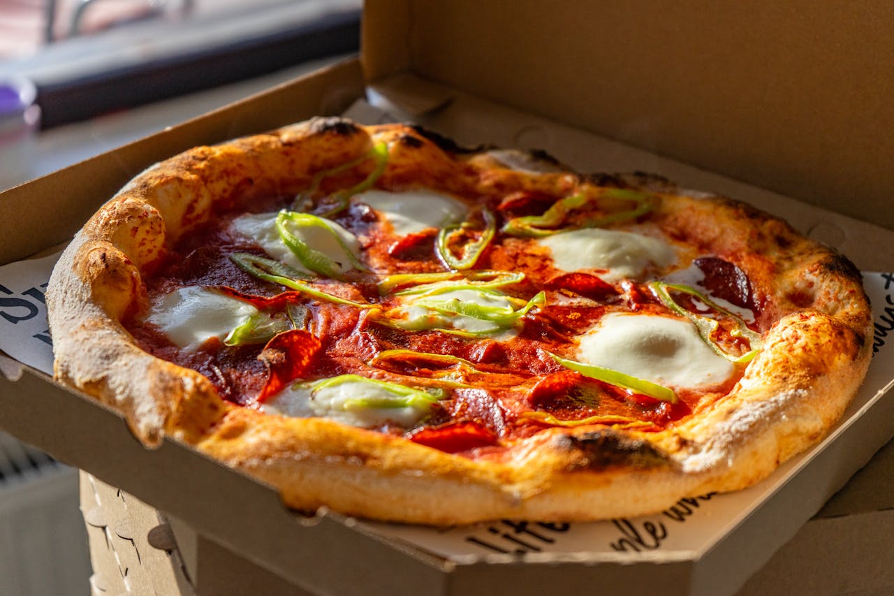heros-img Tasty Neapolitan pizza with fresh ingredients in a cardboard box, perfect for takeout.